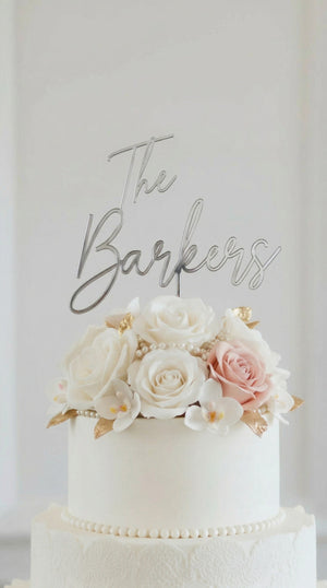 Wedding cake toppers personalized acrylic name sign on white wedding cake with floral decorations on clean white background