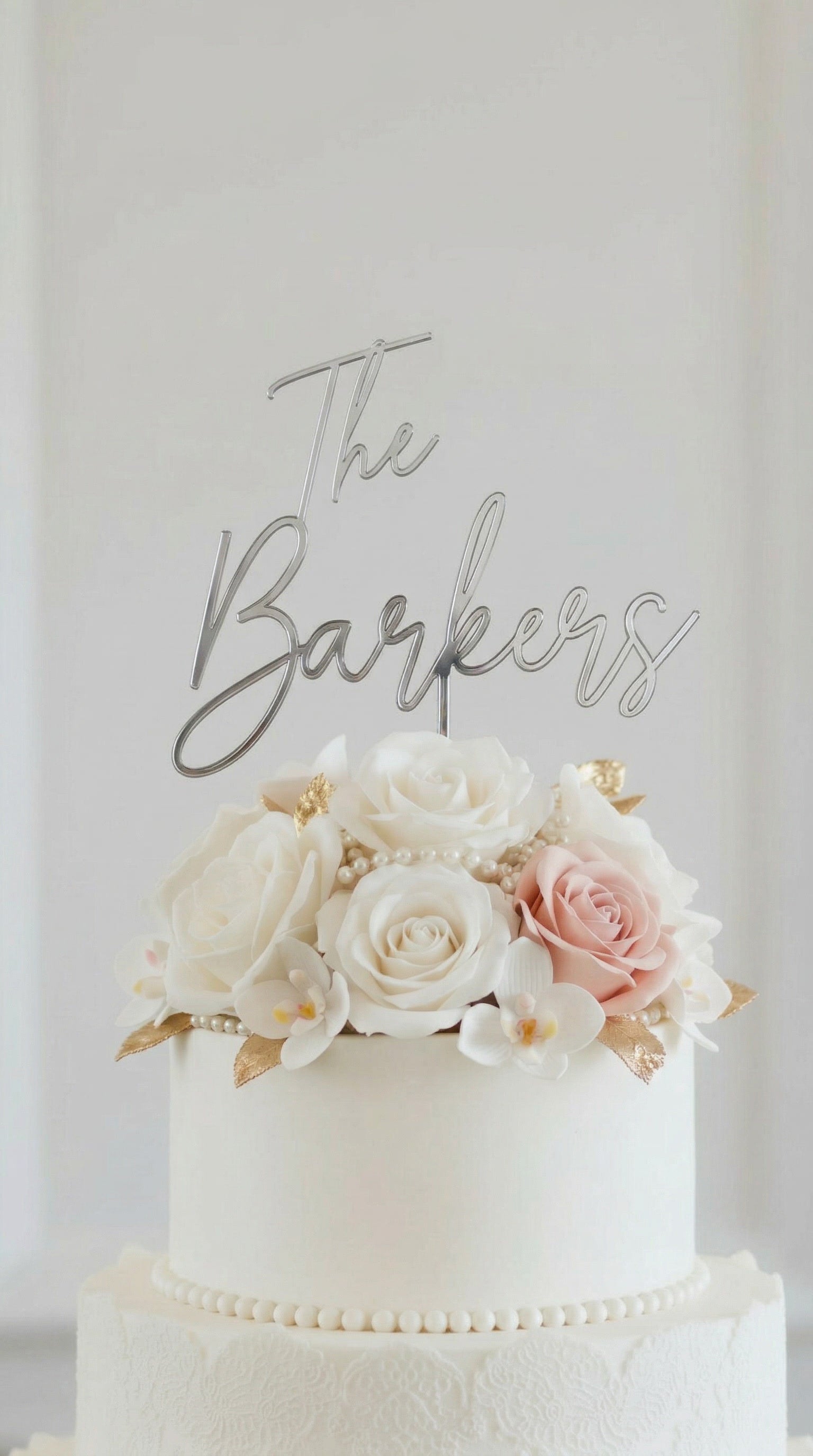 Wedding cake toppers personalized acrylic name sign on white wedding cake with floral decorations on clean white background
